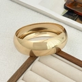 Close-up of a wide polished gold metal cuff bracelet resting on a velvet jewelry box - Metal Bangle / Gold (2957)