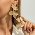 Detail van grote goudkleurige bloemblad oorbellen met geribbelde textuur op een model - Glanzend Goud Overlappend Bloemblad Stijl (3900)