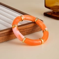 Detail of acrylic bamboo-style bracelet with orange marble texture and gold accents - Orange