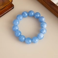 Detail eines himmelblauen Acryl-Perlenarmbands mit wolkiger Textur auf beigem Hintergrund - Armband-Blau