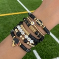 Macro shot of Game Day elastic bracelet set with football charms on a green field - Black Gold Sport Theme (6756)