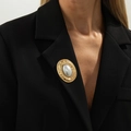 Spilla a pieghe dorata irregolare con perla grigia sul bavero di un blazer nero - Perla Ovale Vintage (0340) / Oro