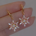 Goldene Schneeflocken-Ohrhänger mit rosa und klaren Kristallen in der Hand gehalten - Schneeflocken-Stil / Rosa