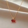 Macro shot of cherry pendant with red beads and sparkling leaf on gold satin fabric - Cherry Necklace (JM2165)