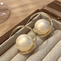 Elegante goldene C-Creolen mit großen cremeweißen Perlen in einer Schmuckschatulle - Gold