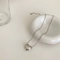 Macro shot of silver puffy heart pendant with snake chain on white ceramic tray - Silver