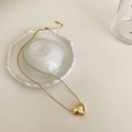 Macro detail of golden heart pendant on snake chain with lobster clasp and extender - Gold