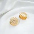 Detailed view of 14K gold shell earrings with ribbed texture on white silk fabric - 7# 14K 23x23x14mm