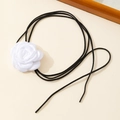 Detailed close-up of a white 3D fabric camellia flower with black velvet cord wrap tie - White