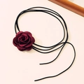Detailed close-up of burgundy fabric rose flower on black long velvet cord choker - Red