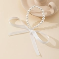 Detailed view of elegant white faux pearl bracelet with a large silky ribbon bow - Bracelet / Bracelet White