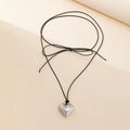 Macro detail of polished heart pendant and black cord bow on a minimalist necklace - Long Sweater Chain Style / Silver