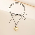Detail of a shiny gold heart pendant on a thin black cord with a decorative bow knot - Long Sweater Chain Style / Gold