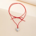 Close-up of a silver heart pendant with red wax cord bow on a minimalist display - Short Choker Style / Red