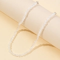 Macro view showing the irregular clear crystal beads and silver metal clasp of the necklace - White