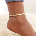 Close-up of a gold flat snake chain anklet worn on a sunlit beach with sandy background - Gold Flat Snake Chain (JC-060G)