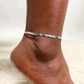 Detailed close-up of a silver herringbone snake chain anklet on a tanned ankle at the beach - Silver Flat Snake Chain (JC-060S)
