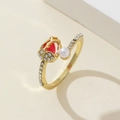 Close-up of golden tulip ring with red gemstone, white pearl, and pavé zircon accents - Red