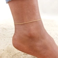 Minimalist gold snake bone chain anklet worn on model ankle with beach sand background - Gold Thin Chain (JC-058G)