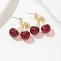 Élégantes boucles d'oreilles cerises rouges avec feuilles dorées sur fond blanc - Rouge