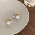 Gros plan de boucles d'oreilles double perles sur plateau céramique et décor rustique - Style Double Perle Dorée / Or