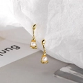 Onregelmatige gouden oorbellen met witte ronde parels op minimalistisch papier - Goud