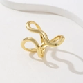 Macro shot of minimalist gold wave-shaped ring with abstract curved lines on white background - Gold