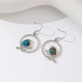 Silver bird on branch earrings with blue gemstone inlay in a circular frame - Silver Earrings