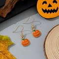 Détail de boucles d'oreilles citrouille orange avec motifs noirs sur fond bois rustique - Style Citrouille d'Halloween aux Yeux Cousus (23)