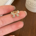 Sparkling gold bow ear cuff with micro-pave zircons worn on a finger for daily fashion - Golden Zircon Bow Style (A-19)