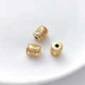 Macro shot of three gold flower embossed cylinder beads on a white ceramic plate - Frosted Embossed Floral Style (11#) / 1 Piece (8x9.5mm)