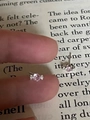 Detailed view of mini candy-shaped pink zircon stud earrings held by hand for size scale - Pink