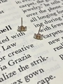 Macro view of mini bow stud earrings with champagne zircon on a book background - Champagne