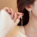 Close-up of elegant silver tassel earrings with crystal knot on a female model - Knot Rhinestone Snake Chain Tassel (A2059)