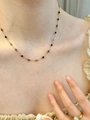 Détail de perles colorées sur une chaîne en or portée par un mannequin en haut à volants - Collier