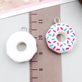 Close-up of white resin donut charms with sprinkles next to a ruler for size - White Donut (17182)