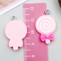 Pendentif sucette en résine rose avec nœud à côté d'une règle pour la taille - Rose