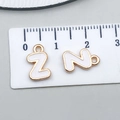 White enamel letter Z and N charms in gold finish with ruler for size reference - Letter Z