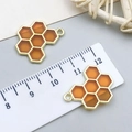 Detailed view of golden honeycomb charms with orange resin beside a measuring scale - Double Sided Orange Bee Honeycomb (13955)