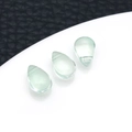 Three light green teardrop glass beads displayed on a white stand with a black background - Grass Green