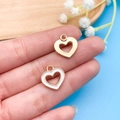 Detailed view of small gold-plated heart charms with white enamel finish on a fingertip - White Enamel Heart (10974)