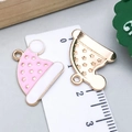 Macro detail of pink enamel Christmas hat pendants showing size on a ruler - Pink Enamel Christmas Hat