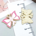 Ciondolo farfalla in smalto rosa e bianco, lega dorata con nastro rosa, misura 20mm - Stile Farfalla Rosa (24869)