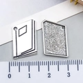 Pendentifs livre et pentagone en argent pour bijoux DIY présentés avec une règle - Livret (12159)