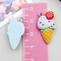 Detail view of 3cm resin ice cream cone charms with red strawberry on a pink ruler - Lake Blue