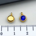 Golden stainless steel pendant with blue faceted gemstone shown beside a measuring scale - September Royal Blue - 6x8.5x4mm Vertical Hole 1.5mm (T2901)