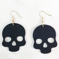 Detalle de pendientes góticos de calavera en cuero negro con ganchos de metal dorado - Estilo de Calavera