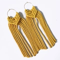 Detail of yellow macrame tassel earrings with golden circular loops in bohemian style - Bright yellow