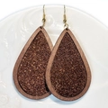 Detail van houten druppelvormige oorbellen met bronzen glitters op een wit bord - Brons Glitter Houten Druppel Stijl (1)