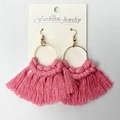 Detailed macro view of handmade pink cotton tassel earrings with gold metal rings - Pink